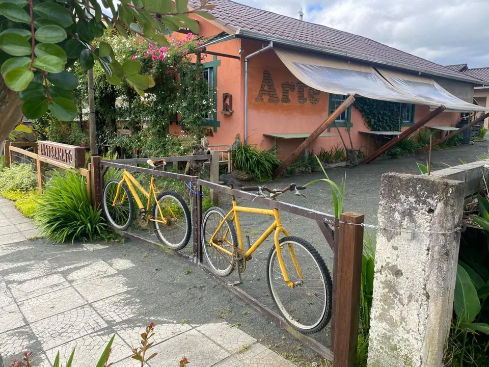 Portão feito com bicicletas amarelas e a casa ao fundo